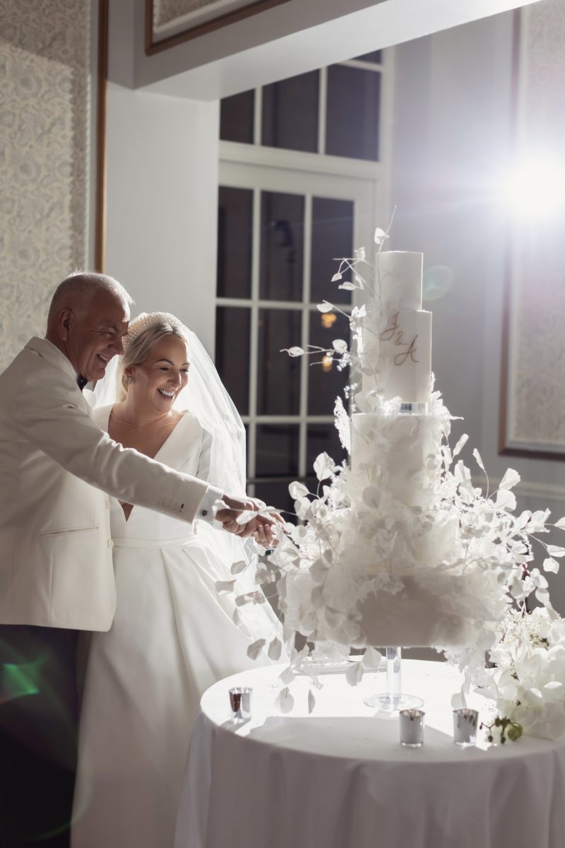 a couple cutting a white wedding cake