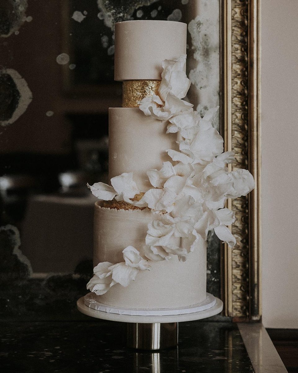 A white wedding cake with gold trim and flowers