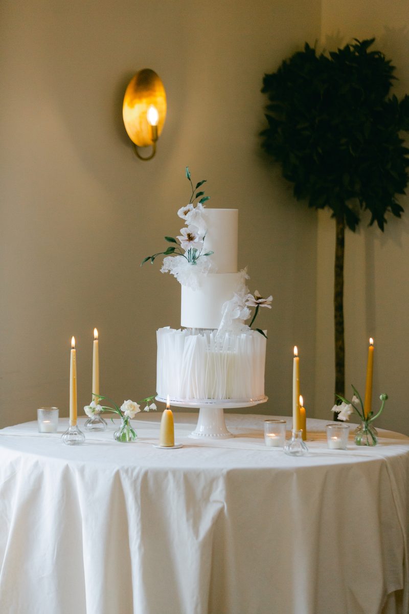 a white wedding cake surrounded by candles